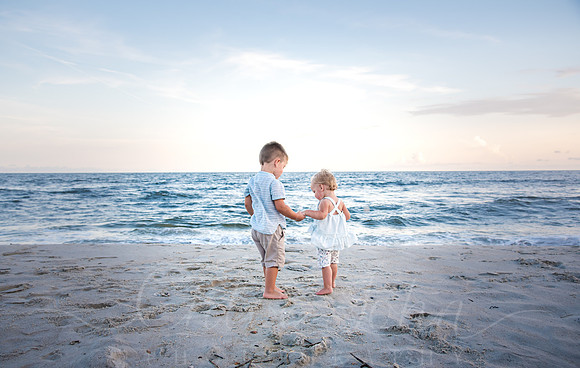 Babies holing hands looking out toward water