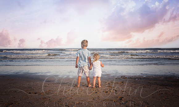 Siblings looking at water- standing on waterline